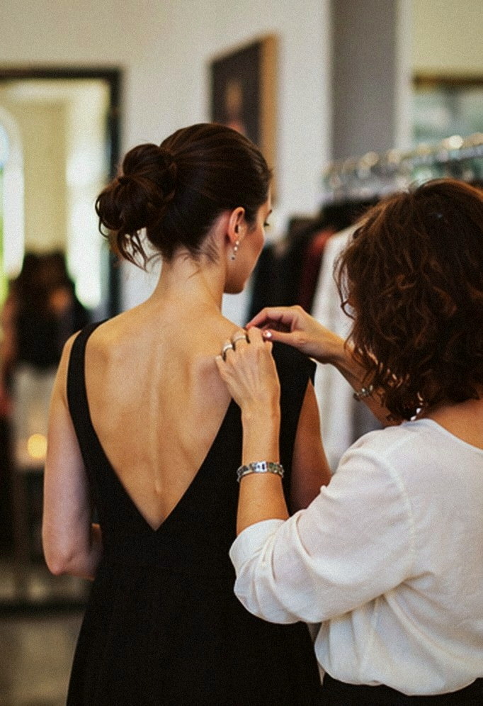 A guest in a black backless dress being styled