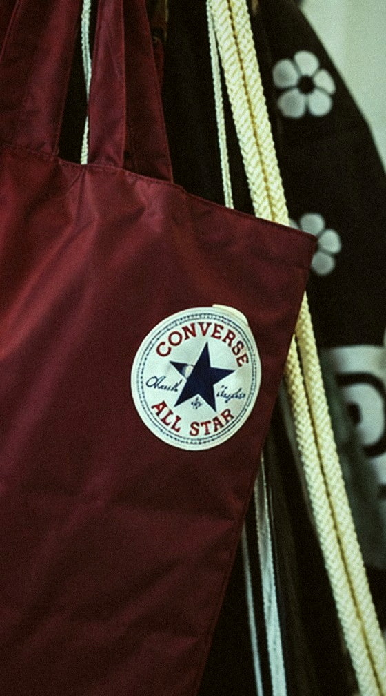 A burgundy tote bag hanging among garments